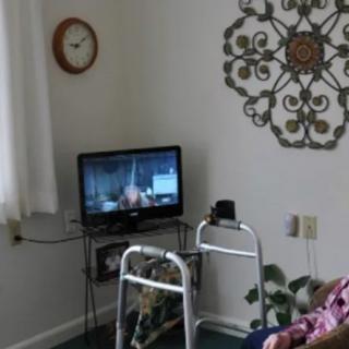 A cozy living room setting with a television, walker, and decorative wall art.
