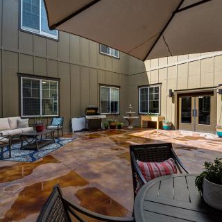 A spacious patio with outdoor seating, a large umbrella, and access to the house through multiple windows and doors.