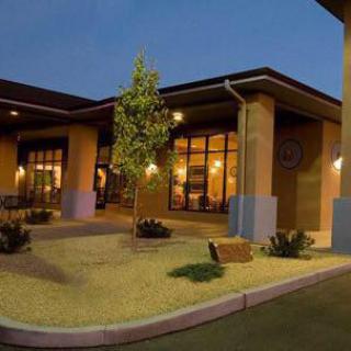 A modern building illuminated at night with landscaped surroundings.
