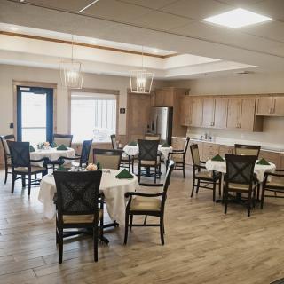 A spacious dining area with several tables and chairs, featuring wooden cabinets and bright lighting.