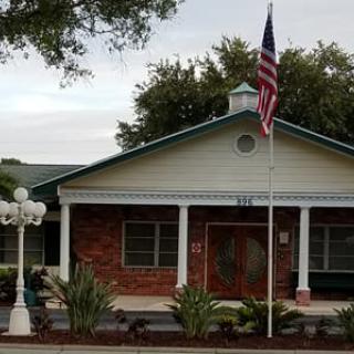 A brick building with a prominent American flag and a well-maintained garden in front.