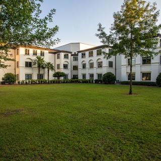 A residential building surrounded by a green lawn and trees during daylight.