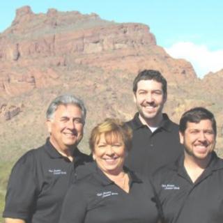 A group of people smiling with a mountainous landscape in the background.