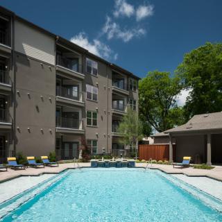 A residential apartment complex with an outdoor swimming pool on a sunny day.