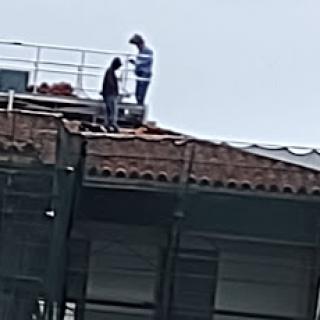 Two workers on a roof, engaged in construction activities.