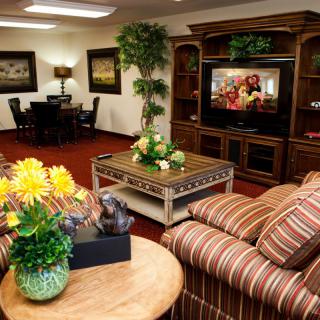 A cozy living room with comfortable sofas, a television, and decorative elements like flowers and paintings.