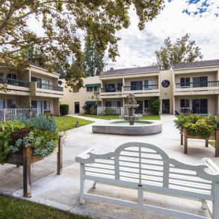 A peaceful courtyard with a central fountain surrounded by a two-story building.