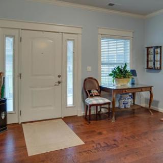 A welcoming entrance with hardwood floors, a small table, and a comfortable chair.