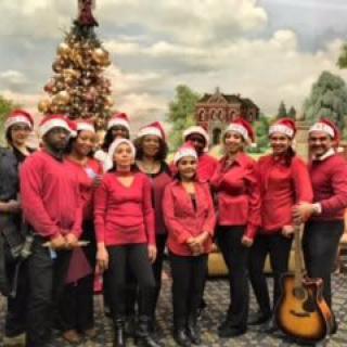 Group of people in festive clothing standing in front of a Christmas tree.
