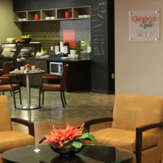 A modern lounge area with comfortable seating and a coffee shop in the background.