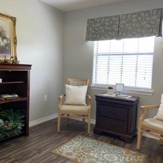 A cozy living room with elegant chairs, a window, and a bookshelf.