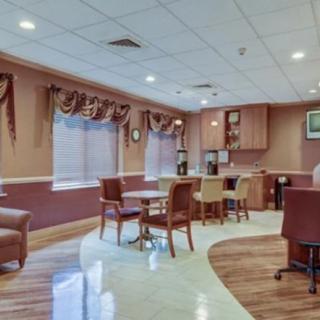 A cozy lounge area with tables and chairs, featuring wood flooring and ceiling lights.