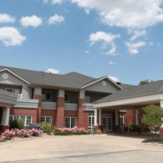 A modern residential building with brick and siding exterior under a partly cloudy sky.