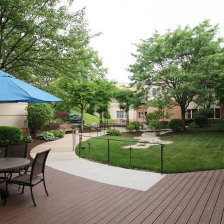 A peaceful backyard garden with outdoor seating and a large umbrella, surrounded by lush greenery.