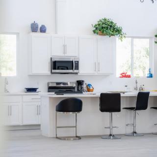 A modern kitchen with white cabinets and bar stools, featuring a clean and minimalist design.