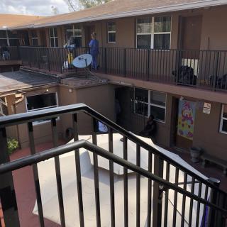 A view of an apartment building with balconies and a satellite dish, seen from a staircase.