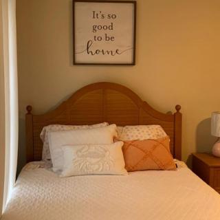 A cozy bedroom with decorative pillows and a framed wall quote.