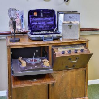 A vintage audio setup featuring a record player, microphone, and various retro audio equipment housed in a wooden cabinet.