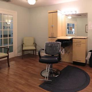A well-lit hair salon with a styling chair, mirrors, and comfortable seating.