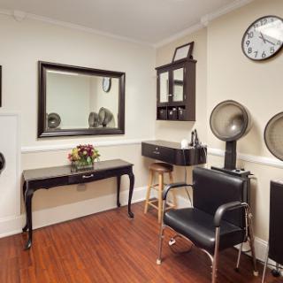 A cozy hair salon interior featuring a mirror, styling station, and comfortable seating.