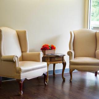 A cozy corner featuring elegant wingback chairs and a small side table adorned with flowers.