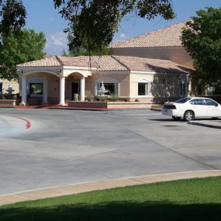 A well-designed building surrounded by greenery and a spacious parking area.