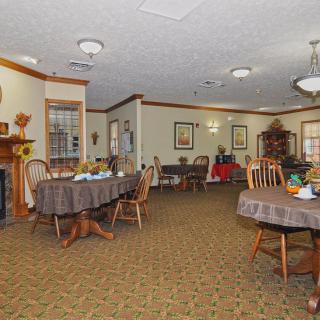 A well-furnished dining room with multiple tables and chairs, decorated with elegant touches and warm lighting.