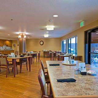 A spacious dining area with several tables and chairs, featuring warm lighting and a welcoming atmosphere.
