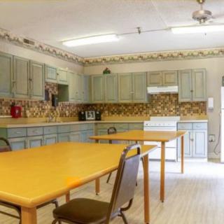 A spacious kitchen with wooden tables and chairs, equipped with cabinets and appliances.