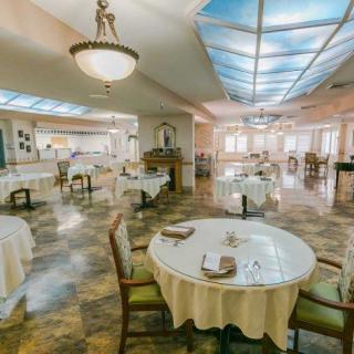 An elegant dining room setup with neatly arranged tables and chairs under a chandelier.