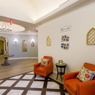 A cozy waiting area with orange chairs and decorative wall art.