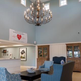 A cozy lobby area featuring a large chandelier, comfortable seating, and a reception desk.