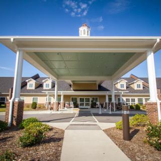 The welcoming entrance of a modern facility under a clear blue sky.