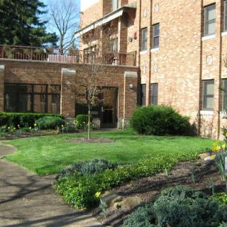 A residential brick building with a well-maintained garden in the foreground.