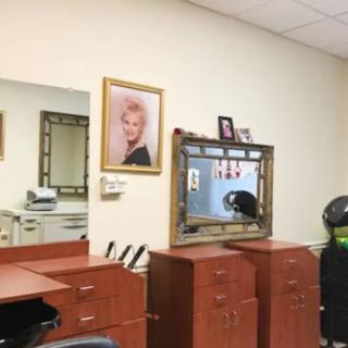 A hair salon interior featuring mirrors, wooden cabinets, and a framed portrait on the wall.