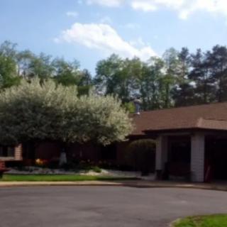 A building surrounded by trees with a clear sky and clouds above.