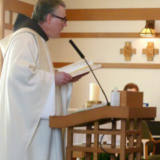 A priest delivering a sermon at the pulpit during a church service.