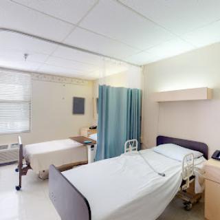 A view of a hospital patient room featuring two beds and a privacy curtain.