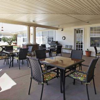 A covered outdoor patio area with tables and chairs arranged for seating.