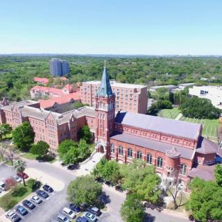 Aerial view of a university campus with historic buildings and surrounding greenery.