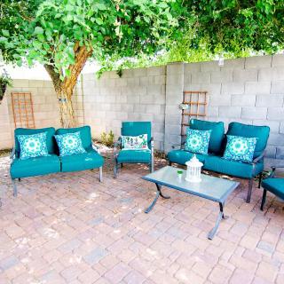 A cozy patio seating area with teal cushioned furniture under a tree.