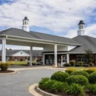 A landscaped entrance to a building with a covered driveway and cupolas.