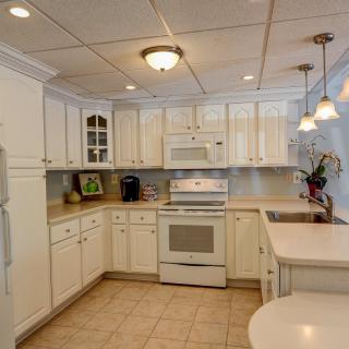 A bright and modern kitchen with white cabinets and tile flooring.