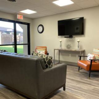A modern living room with a sofa, chairs, and a wall-mounted TV.
