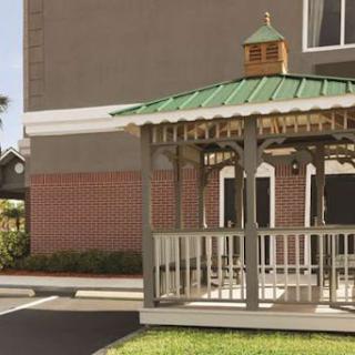 A charming gazebo with a green roof, providing a cozy outdoor space near a building.