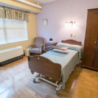 A well-furnished hospital room with a bed and seating area.