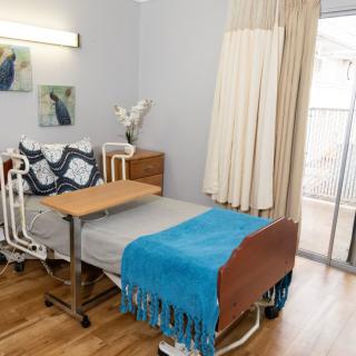 A simple and clean hospital room with a bed, bedside table, and curtains.