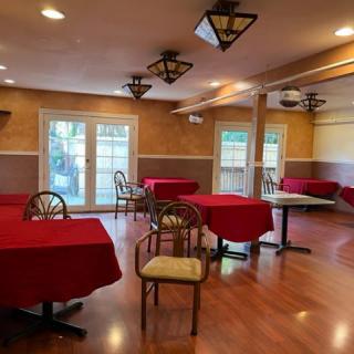 An empty dining area in a restaurant with red tablecloths and wooden floors.