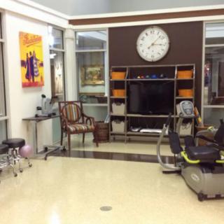 A modern waiting area featuring a television, exercise equipment, and decorative art.