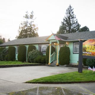 A restaurant building with a green exterior and a welcoming entrance, surrounded by trees.